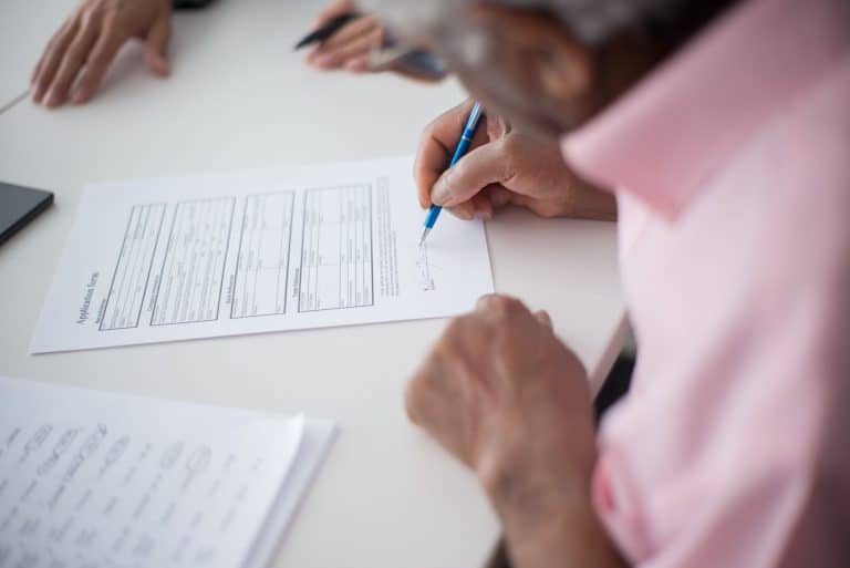 Homme senior signant un acte de révocation testamentaire chez notaire