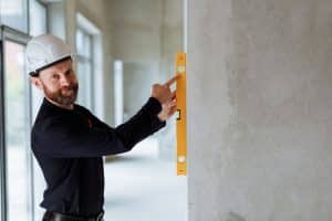 Syndic et artisan inspectant des travaux urgents dans une copropriété française, dégâts visibles
