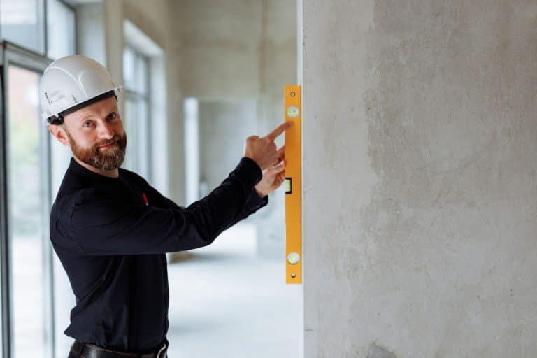 Syndic et artisan inspectant des travaux urgents dans une copropriété française, dégâts visibles